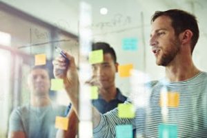 Cropped shot of coworkers using sticky notes on a glass wall during a meeting